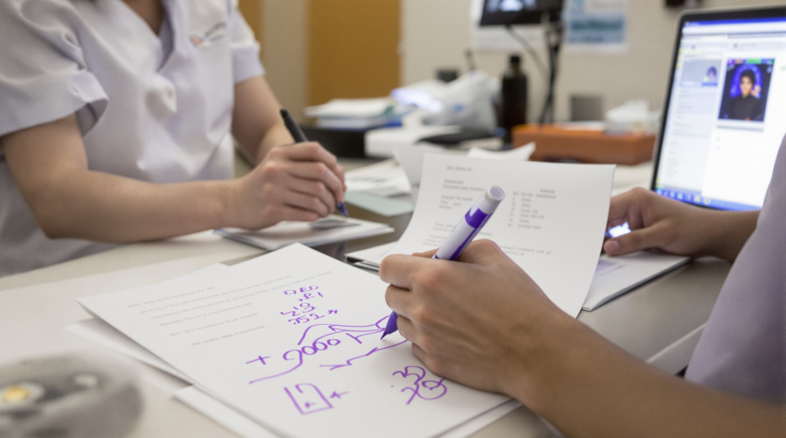A phlebotomist drawing a blood sample from the arm of a patient with vitiligo patches on the hand in a bright clinic